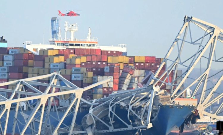 The steel frame of the Francis Scott Key Bridge sit on top of a container ship after the bridge collapsed in Baltimore, Maryland, on March 26, 2024. ©AFP