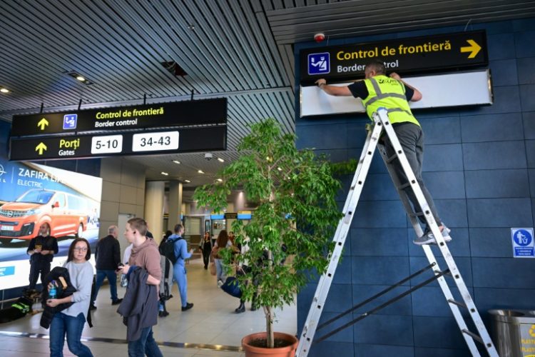 A Romanian worker changes the signs for passengers at Henri Coanda International Airport ahead of Romania and Bulgaria taking a first step into the Schengen visa free travel area on Sunday. ©AFP