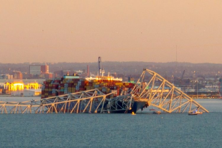 The steel frame of the Francis Scott Key Bridge sits on top of a container ship after it struck the bridge in Baltimore, Maryland, on March 26, 2024. ©AFP