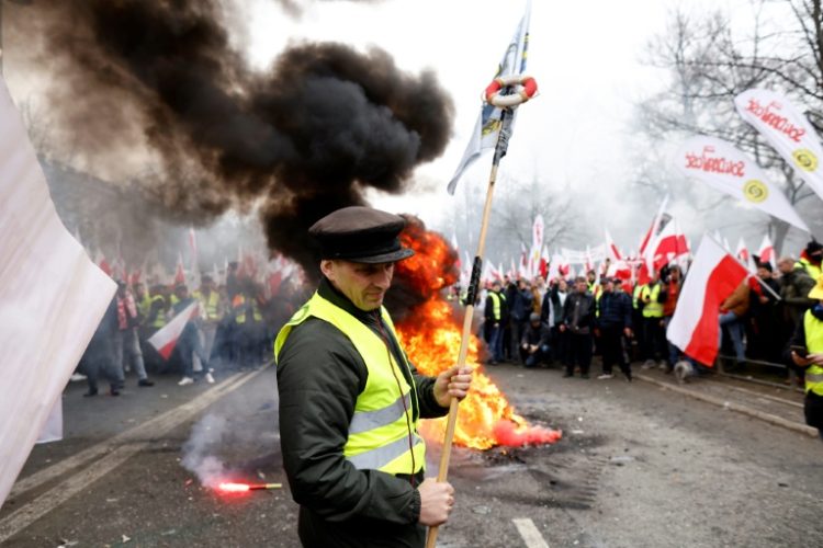 Blowing horns, throwing smoke bombs and firecrackers and lighting fires, the farmers gathered outside the prime minister's office. ©AFP