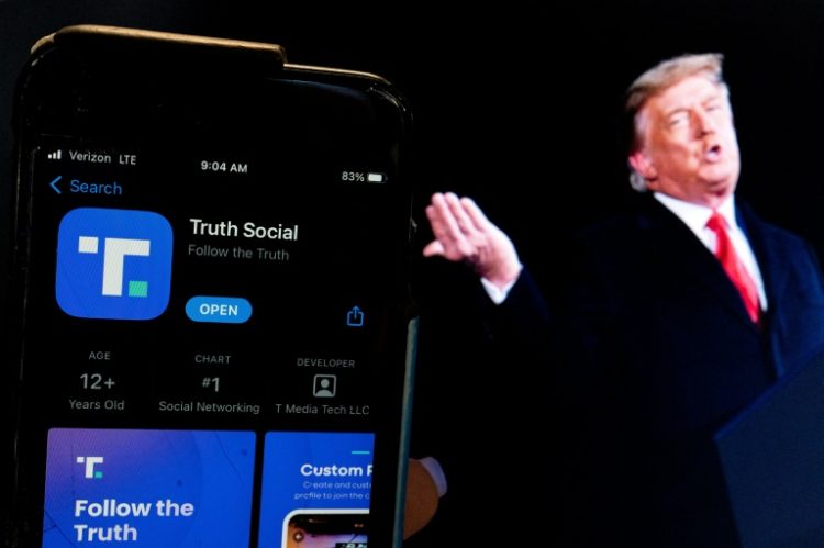 Donald Trump next to a phone screen displaying the Truth Social app. ©AFP