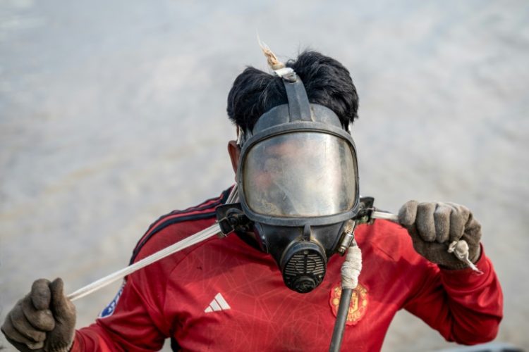 A diver in Myanmar works to recover a sunken ship in the Yangon River, plunging down to attach cables to the wreck and using the power of the tides to bring the boat to shore. ©AFP