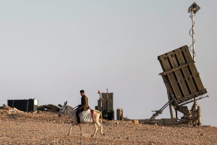 A boy rides a donkey near one of the batteries of Israel's Iron Dome missile defence system at a village not recognised by Israeli authorities in the southern Negev desert . ©AFP