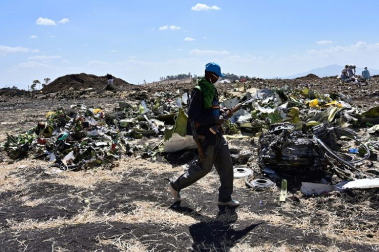 A man walks by a pile of twisted debris at the crash site of an Ethiopian Airways Boeing 737 MAX in March 2019. ©AFP