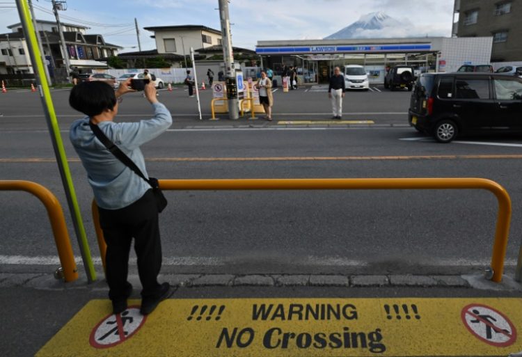 A tourist takes pictures of Mount Fuji in the town of Fujikawaguchiko, Yamanashi prefecture. ©AFP