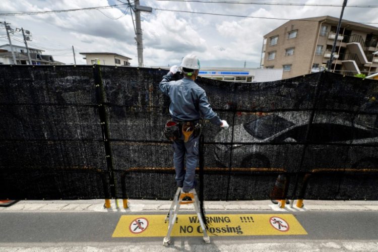 A worker installs a barrier to block the sight of Japan's Mount Fuji to deter badly behaved tourists, in the town of Fujikawaguchiko, Yamanashi prefecture. ©AFP