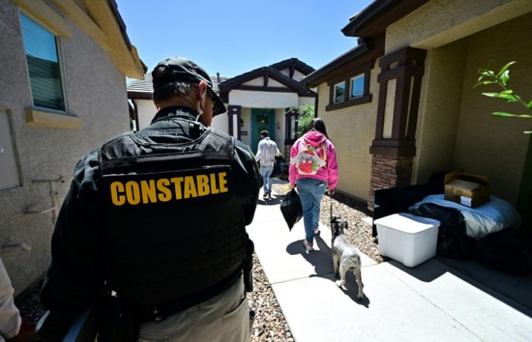 Lennie McCloskey, Constable of Manistee Justice Precint in Maricopa County watches as a family who has just been evicted carry out their belongings on April 15, 2024 in Phoenix, Arizona. ©AFP