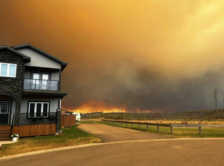 This handout image courtesy of Kosar shows smoke and flames from the fire in Fort McMurray as residents from the Abasand Heights neighborhood evacuate. ©AFP