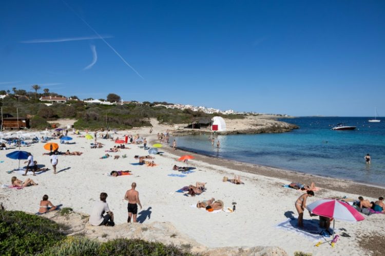 Tourists are flocking to Spain in record numbers, such as these seen sunbathing on the island of Menorca, giving the economy a huge boost. ©AFP