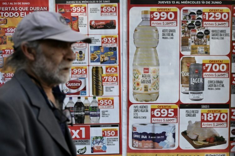 A man walks past food price signs on a street in Buenos Aires on June 13, 2024. ©AFP