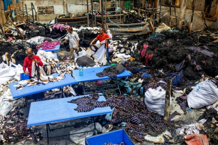 Workers sort through the remains of a garment factory torched during the protests. ©AFP