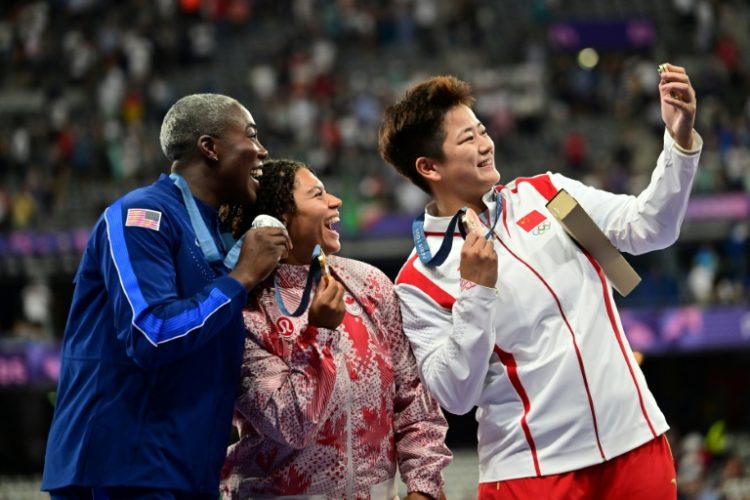 Winners of the women's hammer throw take a selfie with a Samsung flip phone . ©AFP