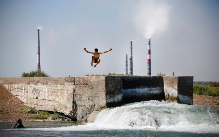 A teenager jumps into the water near the huge Kazakhmys copper plant on the shores of Lake Balkhach in Kazakhstan. ©AFP