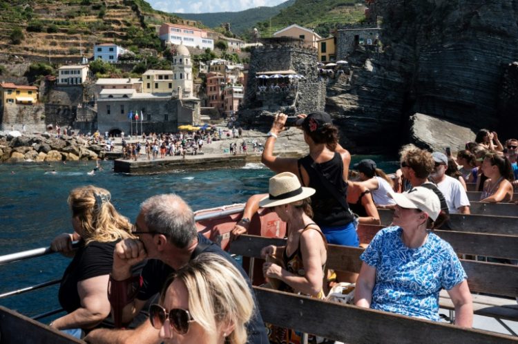 Tour boat passengers gawk at the town of Vernazza, one of the picturesque Cinque Terre villages along the Italian Riviera that are thronged by tourists during the high season. ©AFP