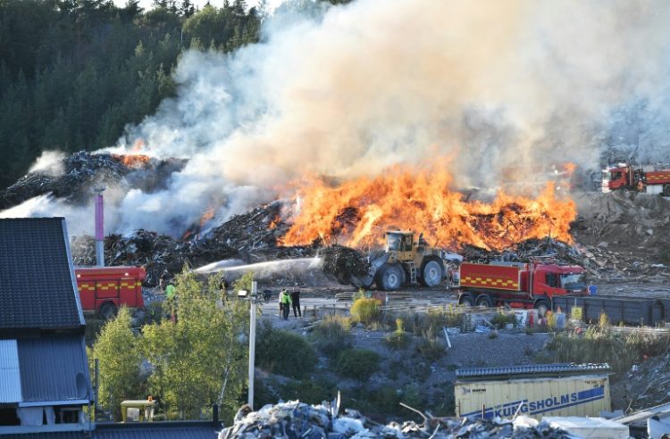 Firefighters tackle a blaze at a Think Pink landfill site at Botkyrka, south of Stockholm. ©AFP