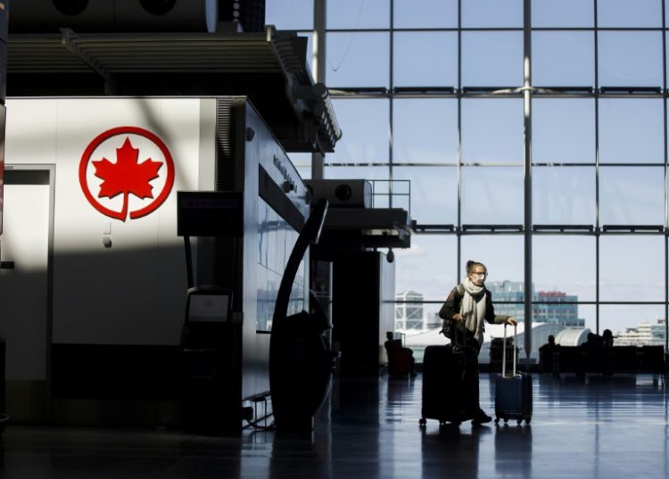 A passenger wheels her luggage near an Air Canada logo at Toronto Pearson International Airport in April 2020. ©AFP