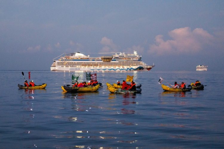 Activists from the NGO "Stop croisieres" and "Extinction Rebellion France" hold banners while they block a cruise ship. ©AFP