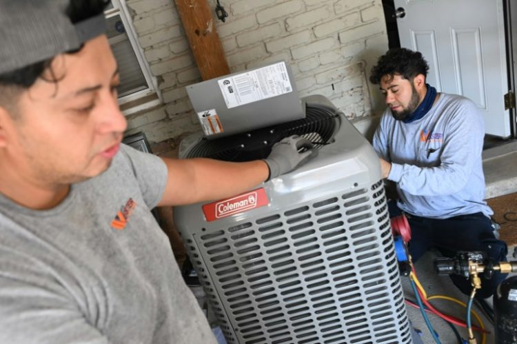 Technicians install a heat pump that replaces the furnace and air conditioner at Su Balasubramanian's home in Washington, DC. ©AFP