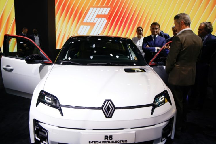 French President Emmanuel Macron stands by a new electric Renault R5 E-Tech at the Paris Motor Show. ©AFP