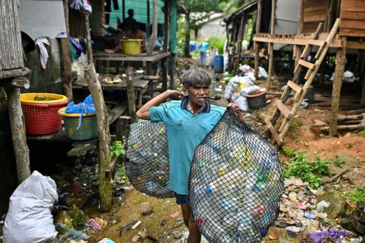 A Moken fisherman carries bags of plastic waste to sell to Tide staff members at his fishing village on Thailand's southern island of Koh Chang. ©AFP