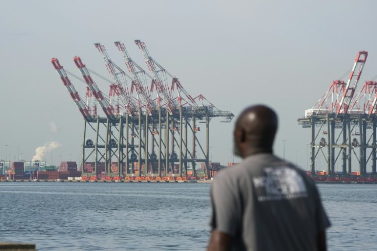 A man walks along a pier in Bayonne as cranes are visible at Port Newark in New Jersey, on October 4, 2024, where a port strike ended. ©AFP