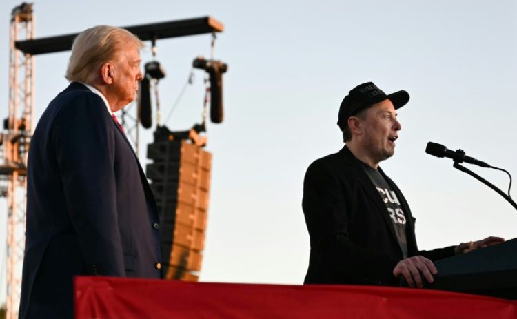 Elon Musk speaks on stage as he joins Donald Trump during a campaign rally. ©AFP