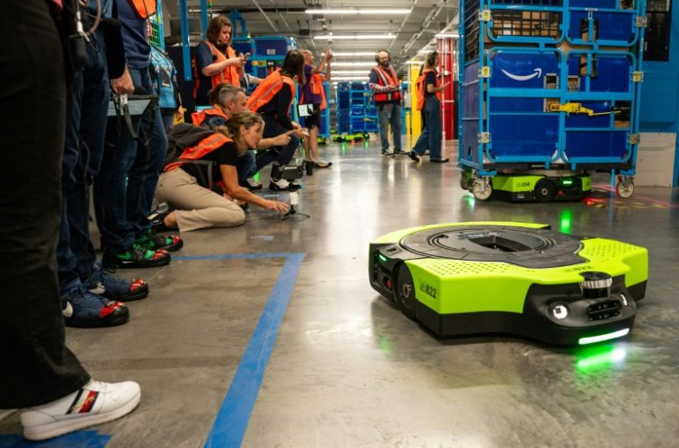 Amazon says logistics center automation, such as robots that safely maneuver loaded carts to waiting trucks, can free human workers for more interesting tasks. ©AFP