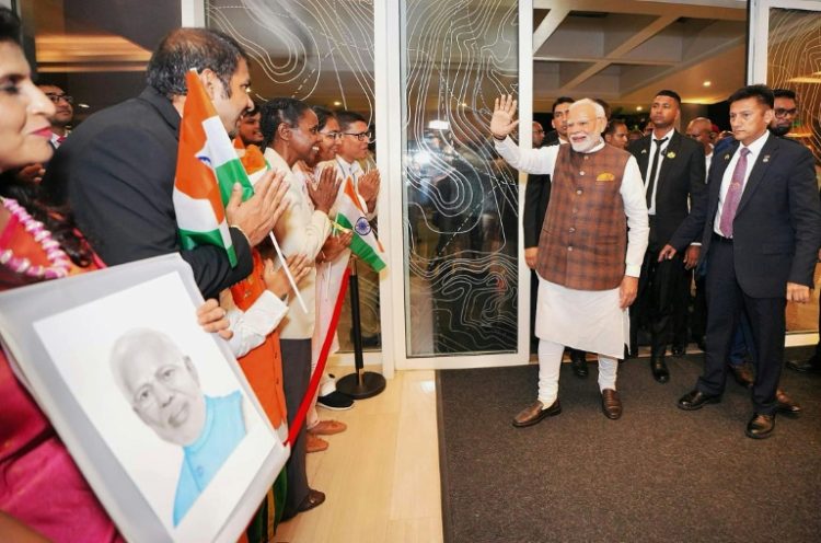 Indian Prime Minister Narendra Modi greets people holding Indian flags as he arrives in Guyana on November 19, 2024. ©AFP