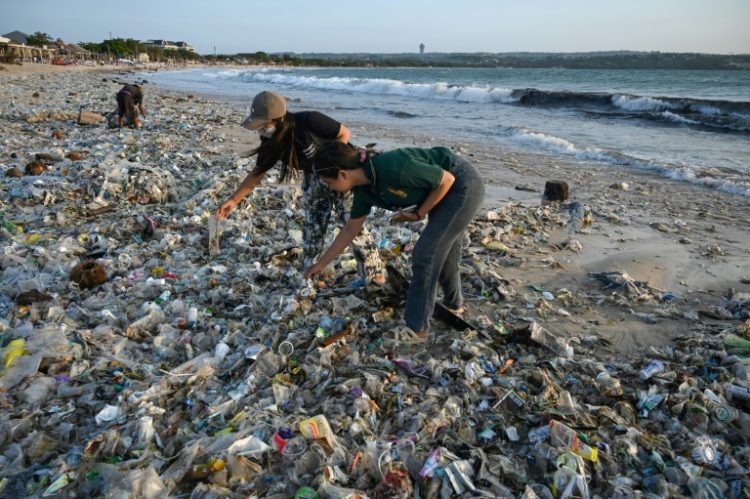 People look through plastic and other debris washed ashore at a beach on Indonesia's resort island of Bali. ©AFP