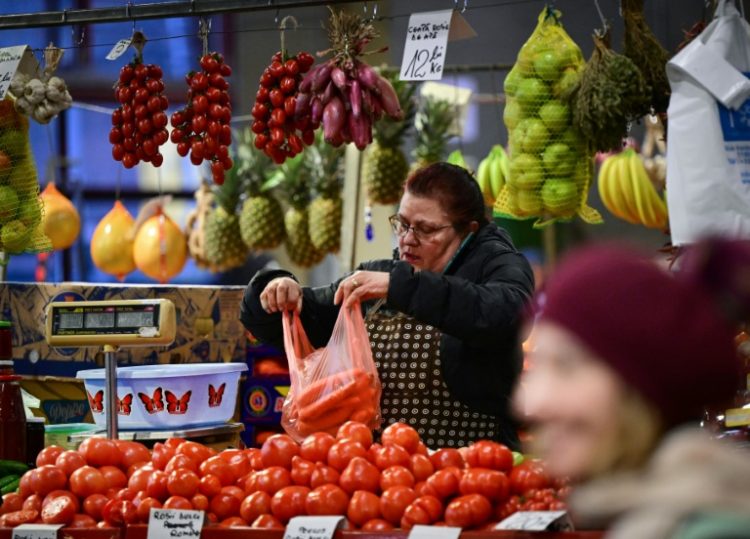 A vendor fills a bag with carrots at Piata Obor marketplace in Bucharest . ©AFP