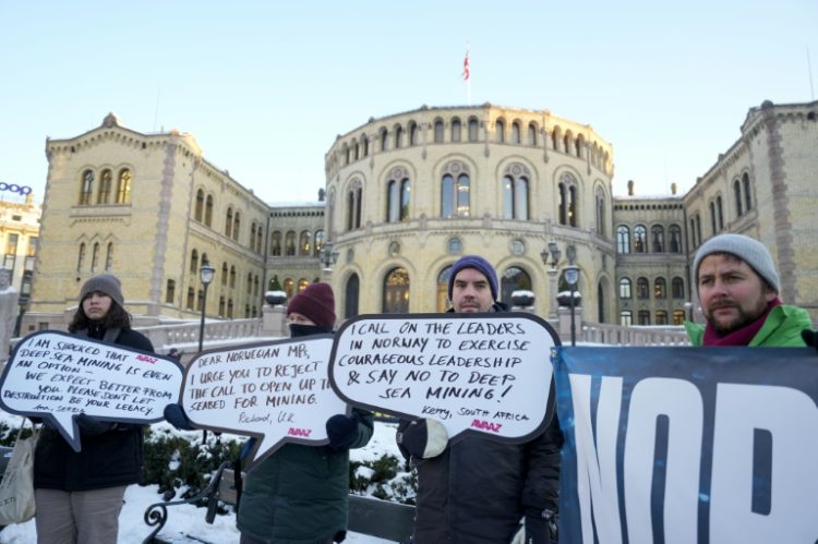 Protesters hold placards during a demonstration against seabed mining outside the Norwegian Parliament building in Oslo. ©AFP