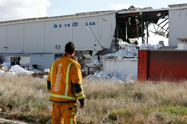 A firefighter stands next to a partially collapsed factory after an explosion killed three people in the town of Ibi. ©AFP