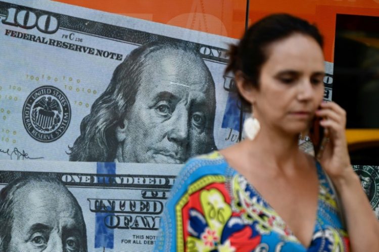 (FILES) A woman walks past an image of US $100 notes in Buenos Aires on December 12, 2023. ©AFP