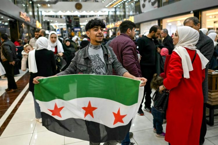 A young man holds a Syrian independence flag in a shopping mall near Sarmada, in the northern province of Idlib. ©AFP