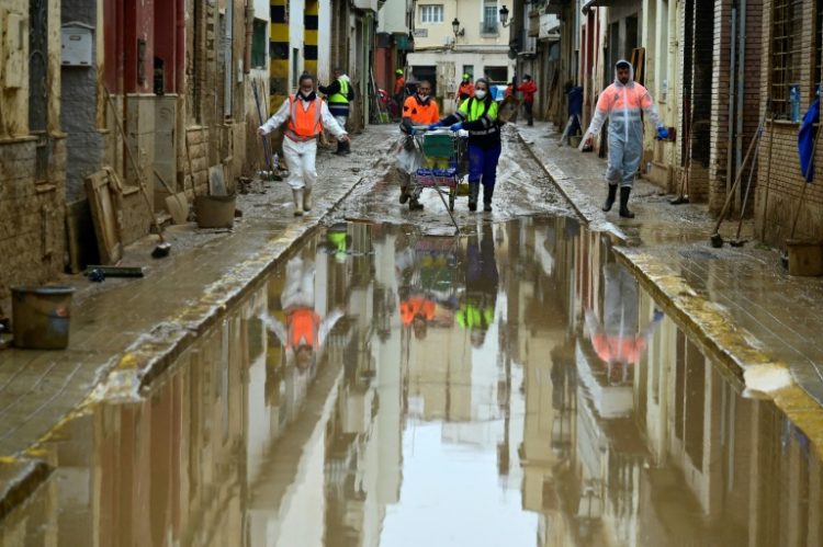 Agents wearing protective jumpsuits take part in cleaning works in a street covered in mud in Paiporta on November 13. ©AFP