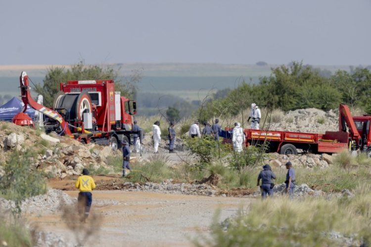 Rescuers and South African Police Service (SAPS) officers carry remains in blue body bags during the rescue operation. ©AFP