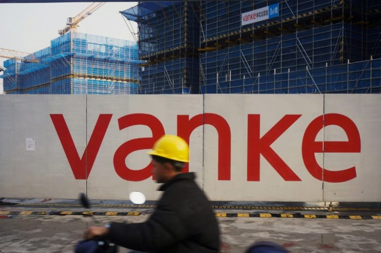 A worker drives past residential buildings under construction by Chinese real estate developer Vanke in Hangzhou in March 2024. ©AFP