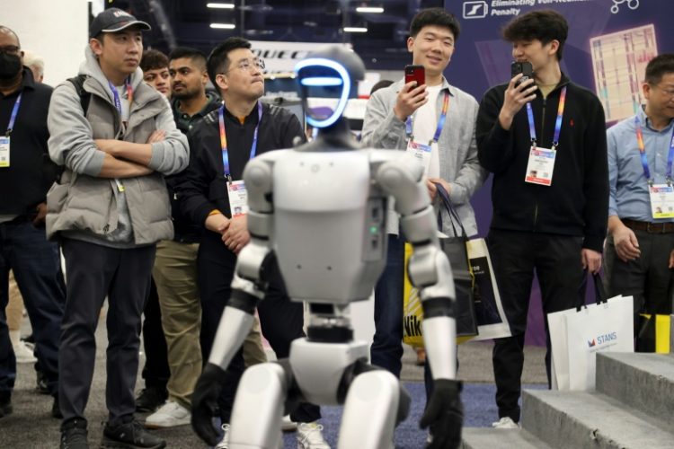 Attendees watch as a robot walks around during a demonstration at the Unitree Robotics booth during the Consumer Electronics Show (CES) in Las Vegas. ©AFP