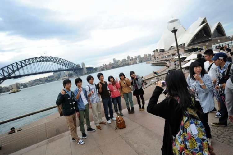 A group of Japanese tourists pose for photographs at Sydney Harbour in 2012. Today around 17.5 percent of Japanese citizens hold valid passports. ©AFP