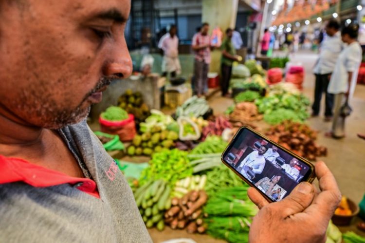 A man watches a live broadcast of Sri Lanka's President Anura Kumara Dissanayake presenting the 2025 budget to parliament . ©AFP