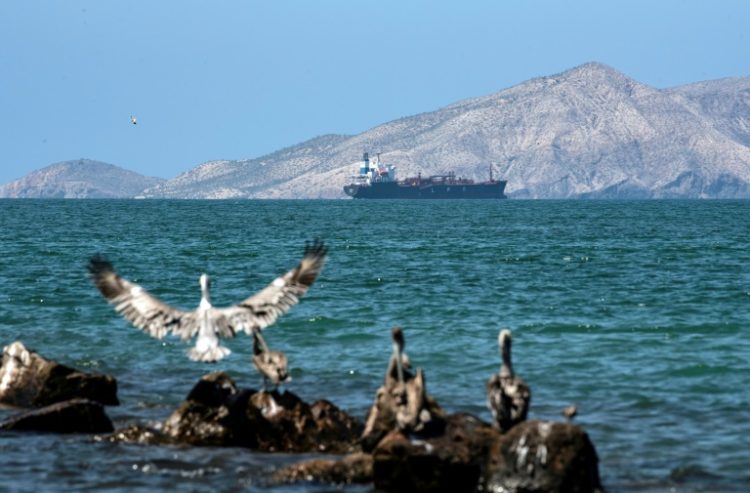 A tanker sails near an oil refining plant of state-owned Petroleos de Venezuela (PDVSA) in Puerto La Cruz in November 2021. ©AFP