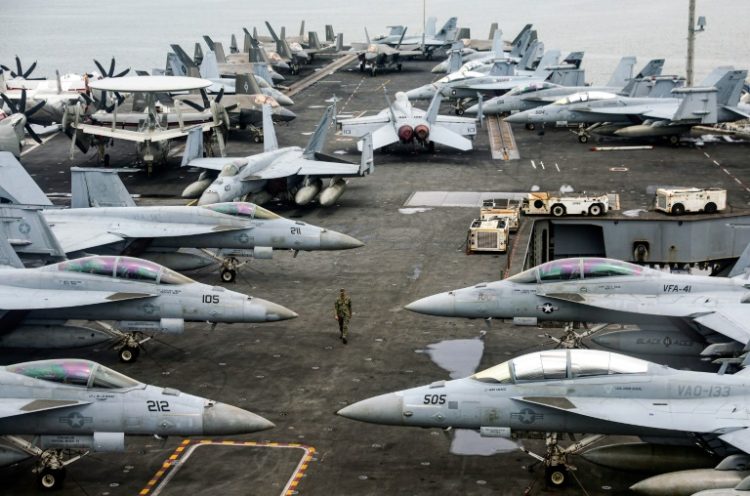 A US Navy officer walks past fighter jets parked on the flight deck of the USS Abraham aircraft carrier. ©AFP